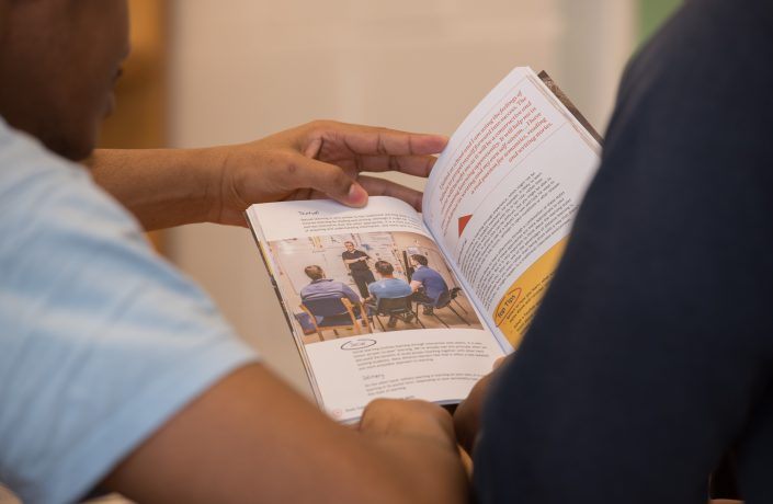 Learners reading PET handbook