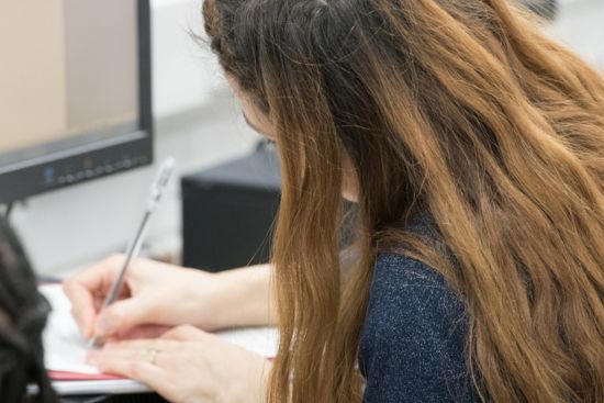 Image of a woman writing at a desk